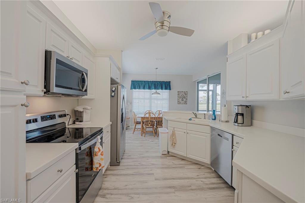 Kitchen featuring stainless steel appliances, a peninsula, light countertops, and white cabinets