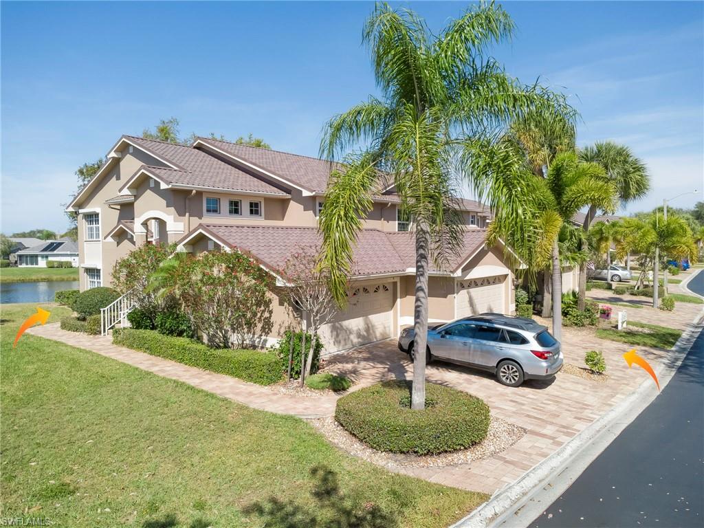 View of front of home featuring decorative driveway, stucco siding, a front lawn, a tiled roof, and a water view