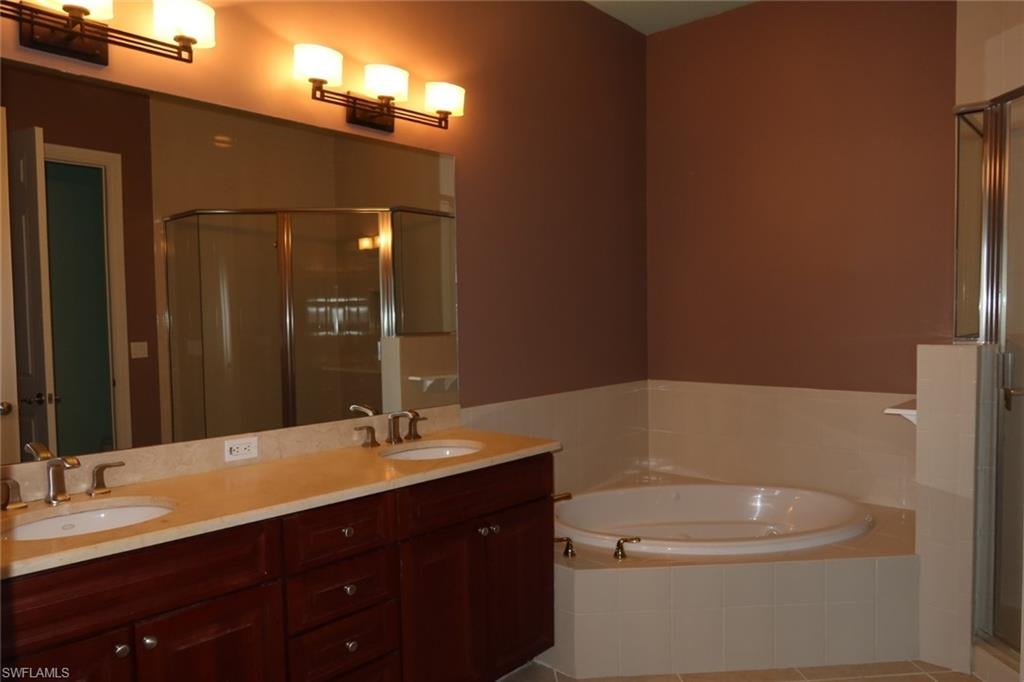 Double vanity with dual sinks, a large framed mirror, and a built-in jetted tub