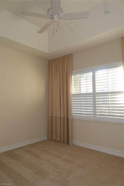 Room featuring a tray ceiling with a ceiling fan, plush carpeting, and plantation shutters
