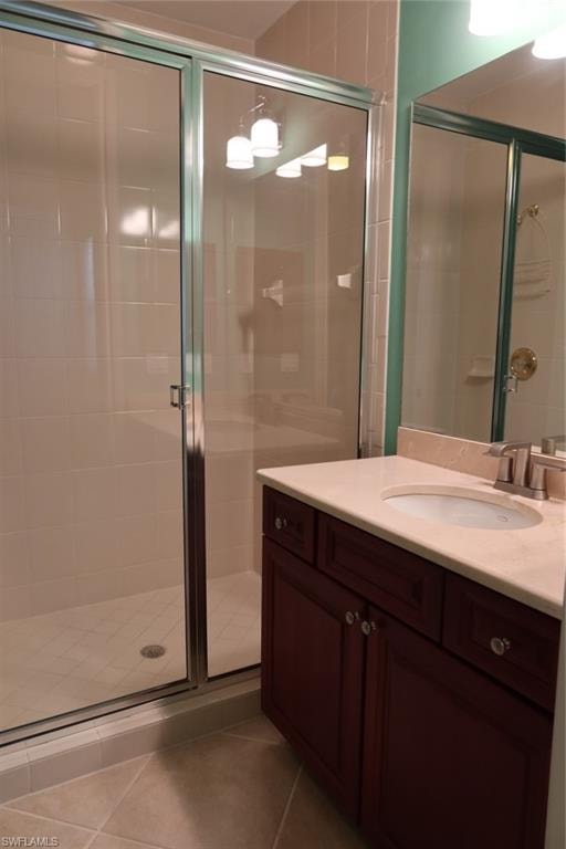 Bathroom featuring a glass-enclosed shower with tile surround, a dark wood-finish vanity with an integrated sink, a light-toned countertop, and brushed nickel fixtures