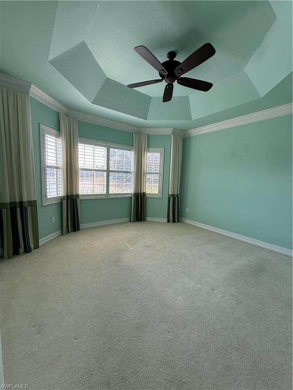 Master bedroom with a ceiling fan, carpet, healthy amount of natural light, a tray ceiling, and ornamental molding