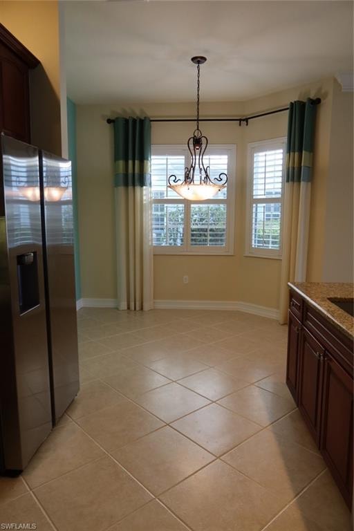 Dining area featuring a bay window with plantation shutters, a decorative ceiling fixture, and neutral-toned tile flooring