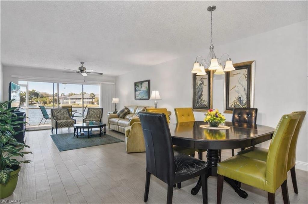 Dining space with a ceiling fan, hanging lights, a textured ceiling, and light wood-style flooring