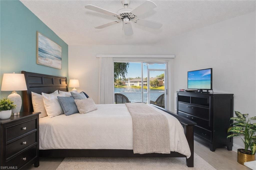 Bedroom with access to exterior, a ceiling fan, light wood-type flooring, and a textured ceiling