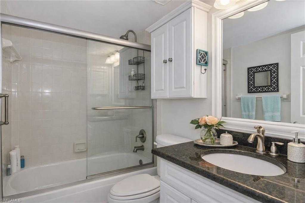 Bathroom with vanity and bath / shower combo with glass door