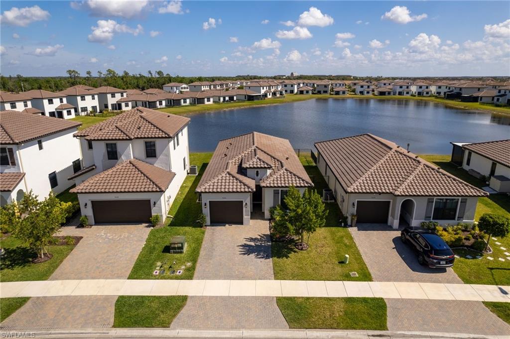 View of front of property with a garage, stucco siding, a water view, driveway, and a residential view