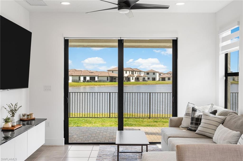 Living room with ceiling fan, light tile patterned flooring, recessed lighting, and a water view