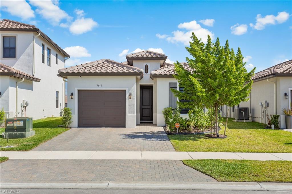 Mediterranean / spanish home with stucco siding, decorative driveway, a front lawn, and an attached garage