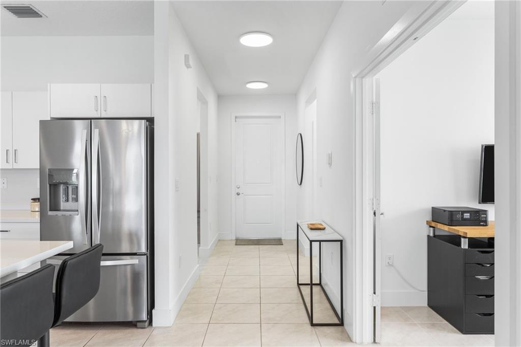 Kitchen featuring stainless steel fridge with ice dispenser, light countertops, light tile patterned floors, and white cabinetry