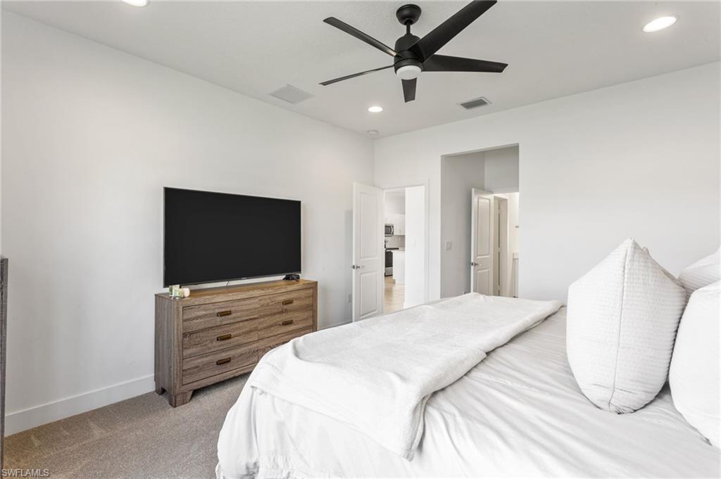 Carpeted bedroom with ceiling fan and recessed lighting
