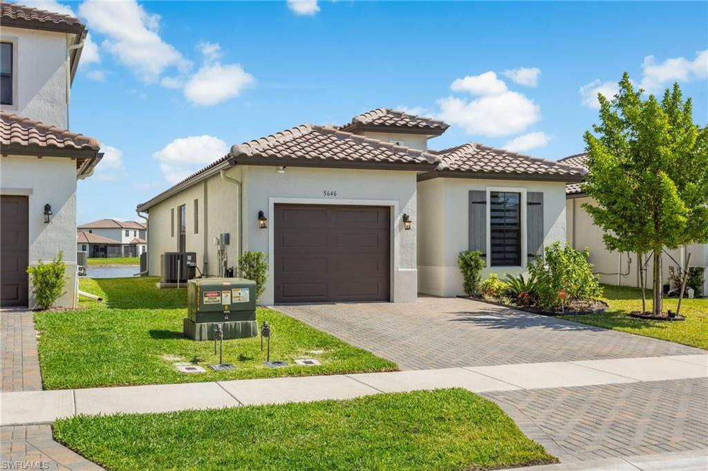 Mediterranean / spanish home with stucco siding, a front yard, a tile roof, and decorative driveway