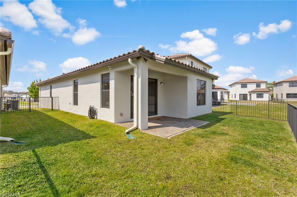 Back of property with stucco siding, a patio, a fenced backyard, a tile roof, and a residential view