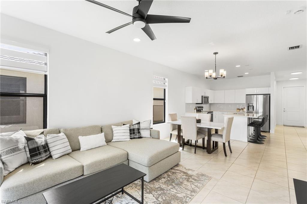 Living room with a ceiling fan, suspended lighting, and light tile patterned floors