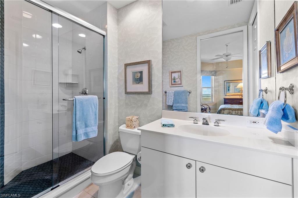 Bathroom with vanity, connected bathroom, a shower stall, and wallpapered walls
