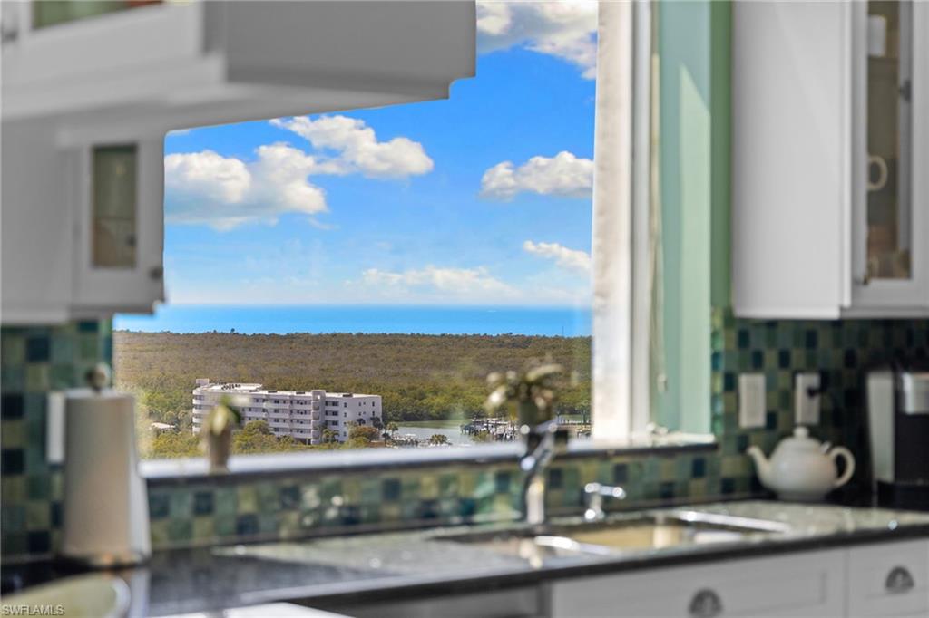 Kitchen view of glass insert cabinets, decorative backsplash, white cabinets, and nearby water