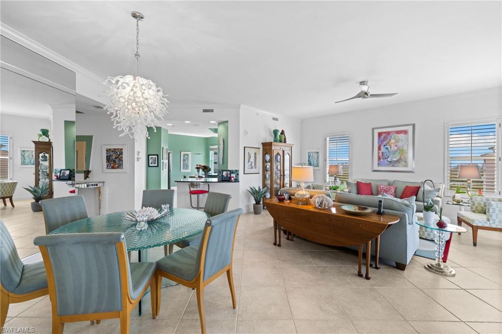 Dining space with ceiling fan, suspended lighting, ornamental molding, and light tile patterned floors
