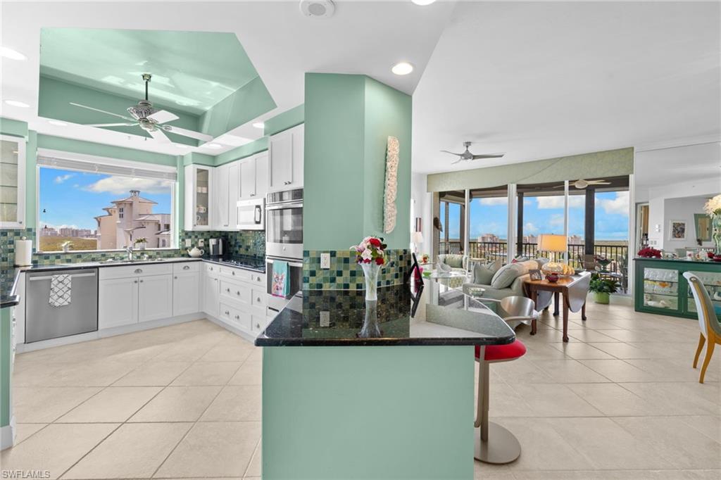Kitchen featuring a ceiling fan, white cabinets, a kitchen breakfast bar, backsplash, and recessed lighting