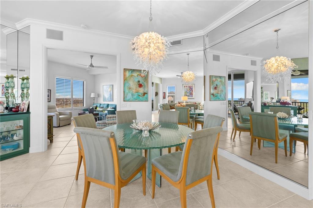 Dining area with hanging lights, ceiling fan, ornamental molding, and light tile patterned floors