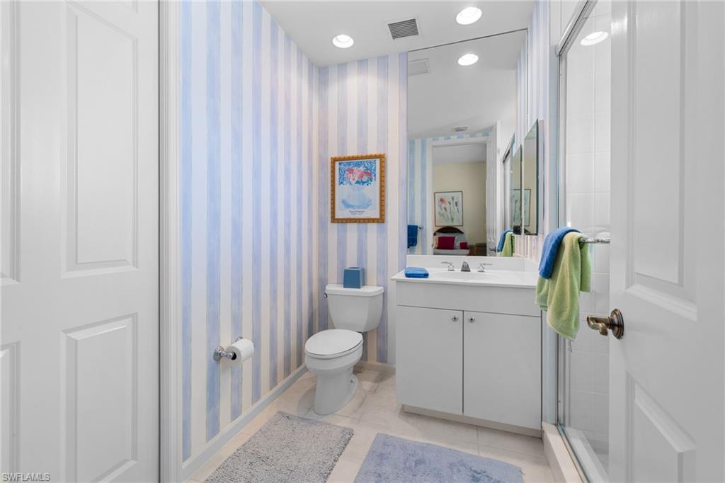 Full bathroom featuring wallpapered walls, vanity, light tile patterned floors, recessed lighting, and a shower