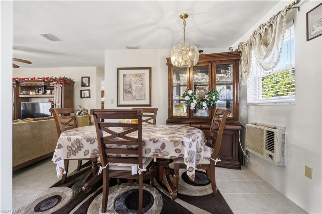 Dining space featuring a chandelier and a wall mounted air conditioner