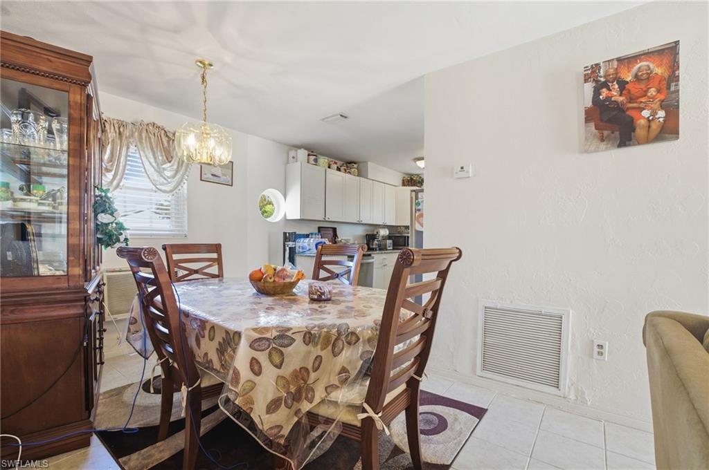 Dining area featuring light tile patterned floors, a chandelier, and a textured wall