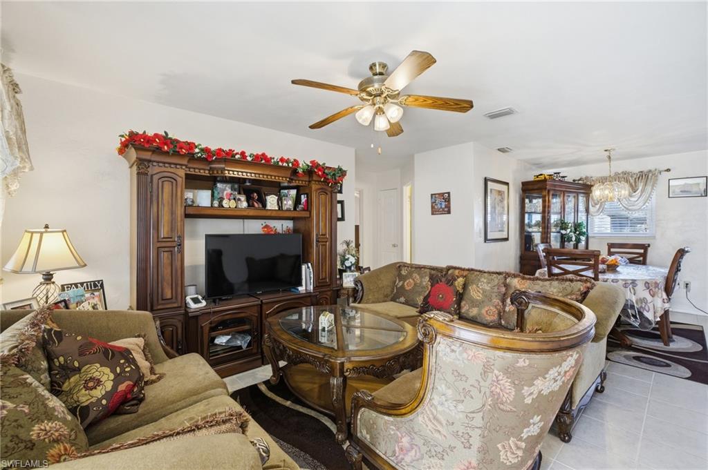 Living room featuring light tile patterned flooring, a chandelier, and a ceiling fan