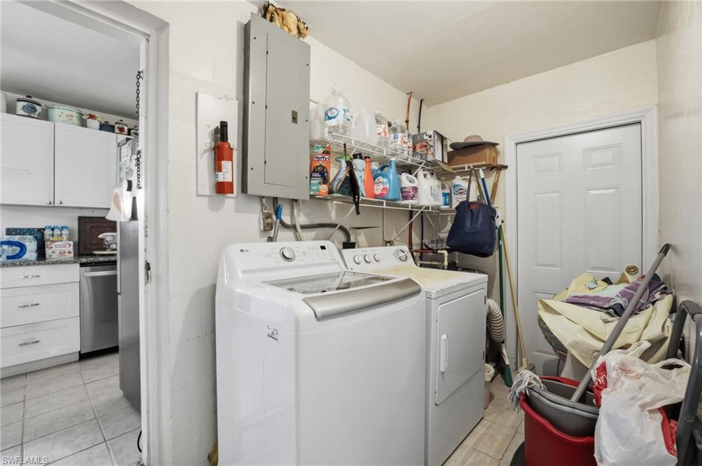Laundry area with electric panel, washing machine and clothes dryer, and light tile patterned floors