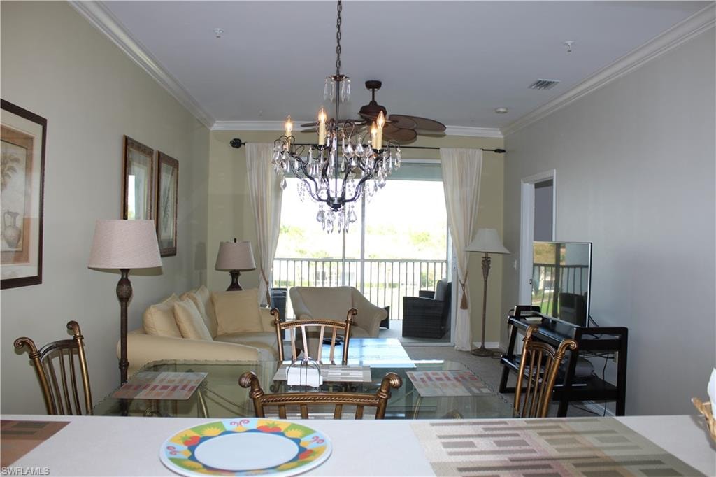 Living area with crown molding, suspended lighting, and carpet flooring