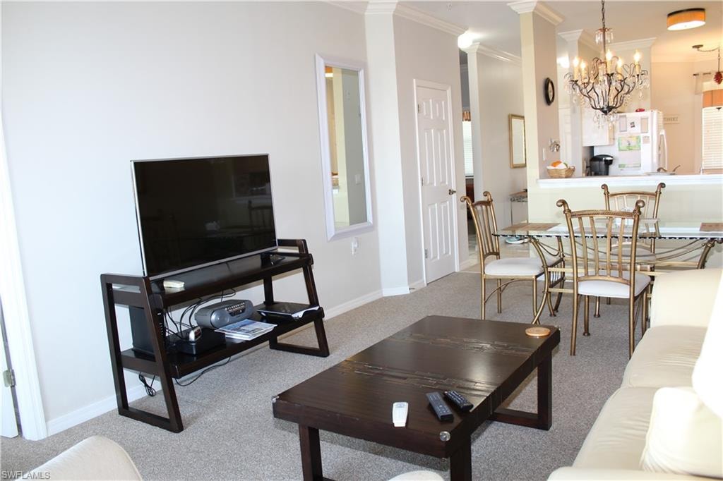 Living room featuring crown molding, light colored carpet, and suspended lighting
