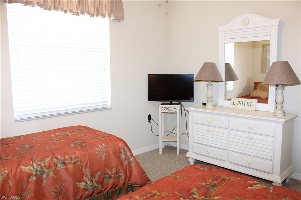 Bedroom featuring light carpet and baseboards