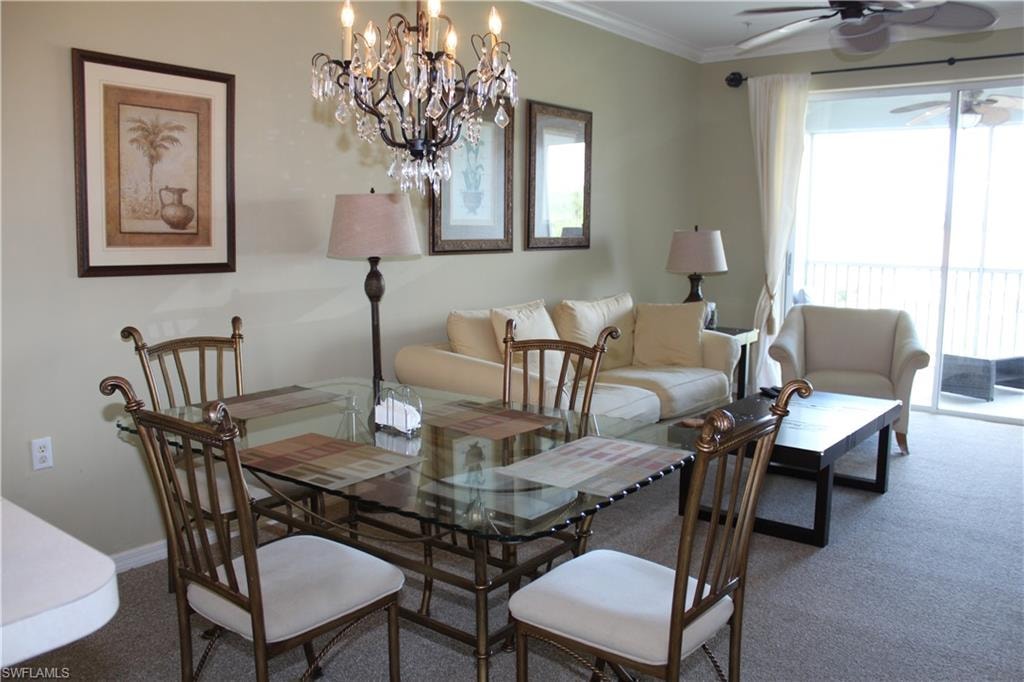 Carpeted dining room with a ceiling fan, suspended lighting, and crown molding