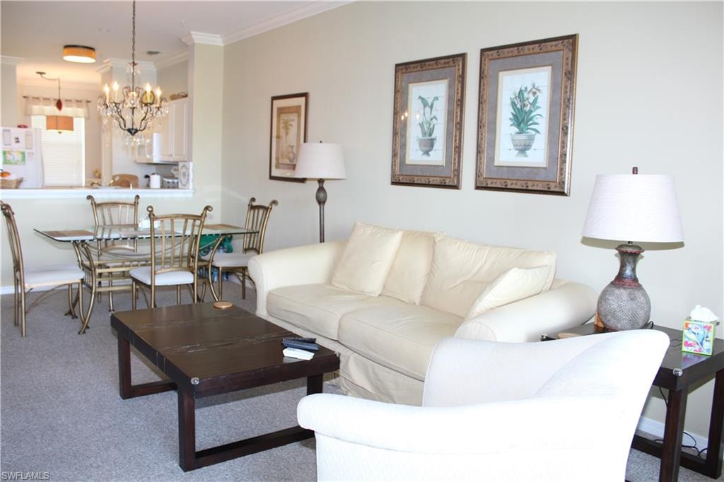 Carpeted living area with crown molding and hanging lights