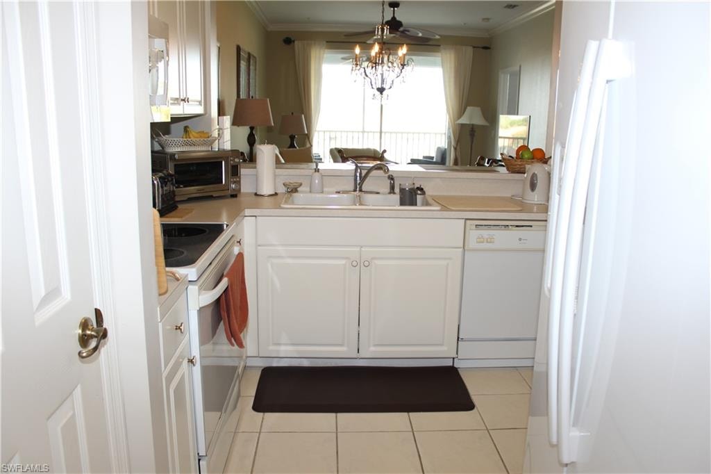 Kitchen with white appliances, white cabinets, light countertops, ceiling fan, and light tile patterned floors