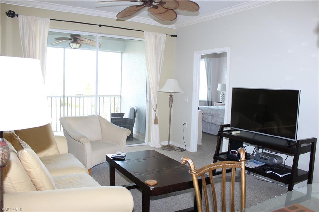 Living area featuring ceiling fan, ornamental molding, and carpet flooring