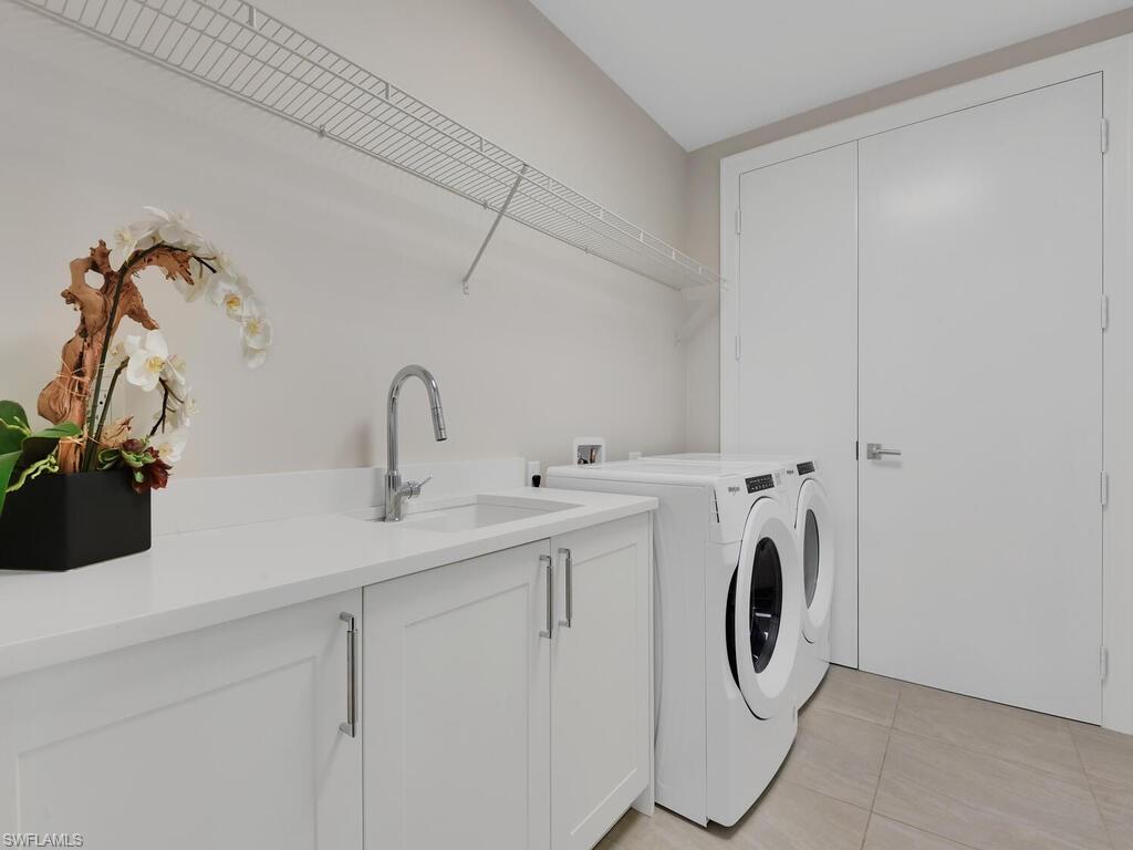 Laundry area with light tile patterned flooring, cabinet space, and washer and dryer