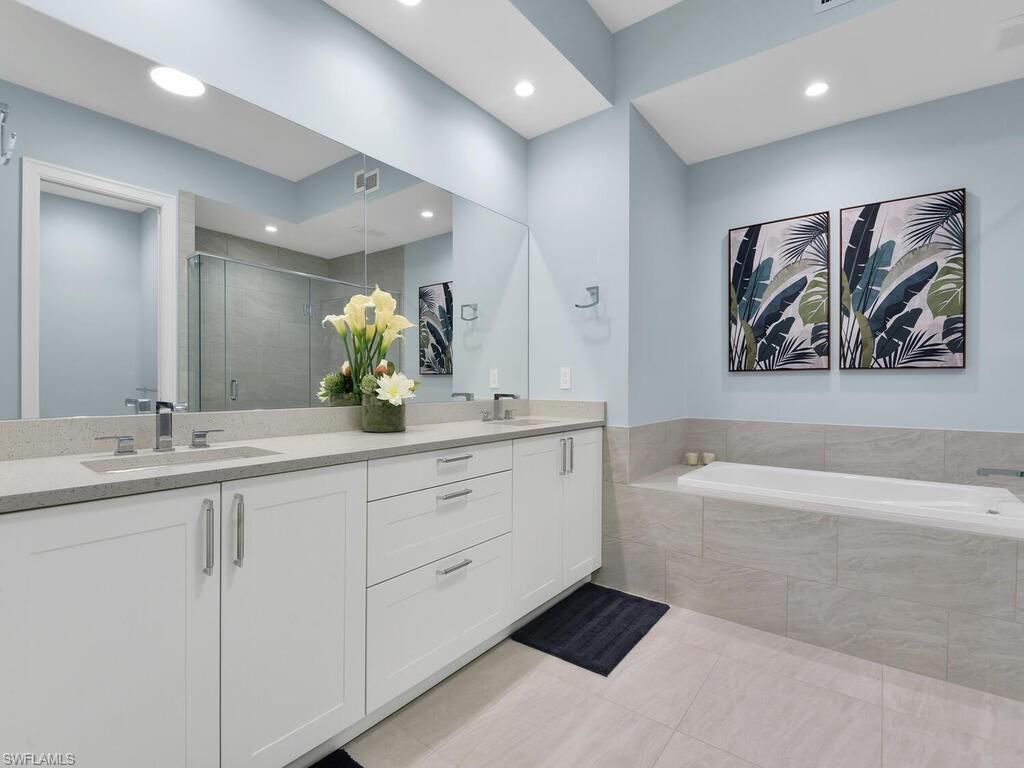 Bathroom with double vanity, a shower stall, a bath, light tile patterned flooring, and recessed lighting