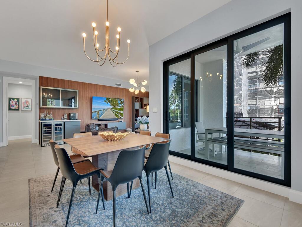 Dining space with hanging lights, wood walls, light tile patterned floors, and beverage cooler