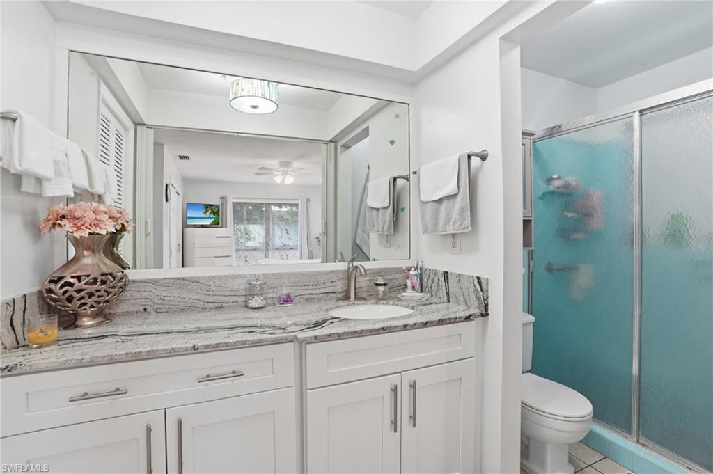 Full bathroom featuring vanity, a shower stall, a ceiling fan, and light tile patterned floors