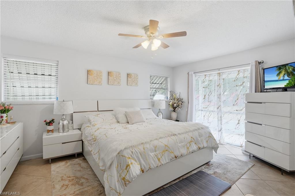 Bedroom with light tile patterned flooring, a ceiling fan, and a textured ceiling