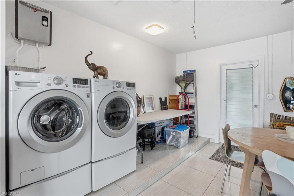 Laundry area featuring water heater, washer and clothes dryer, and light tile patterned floors