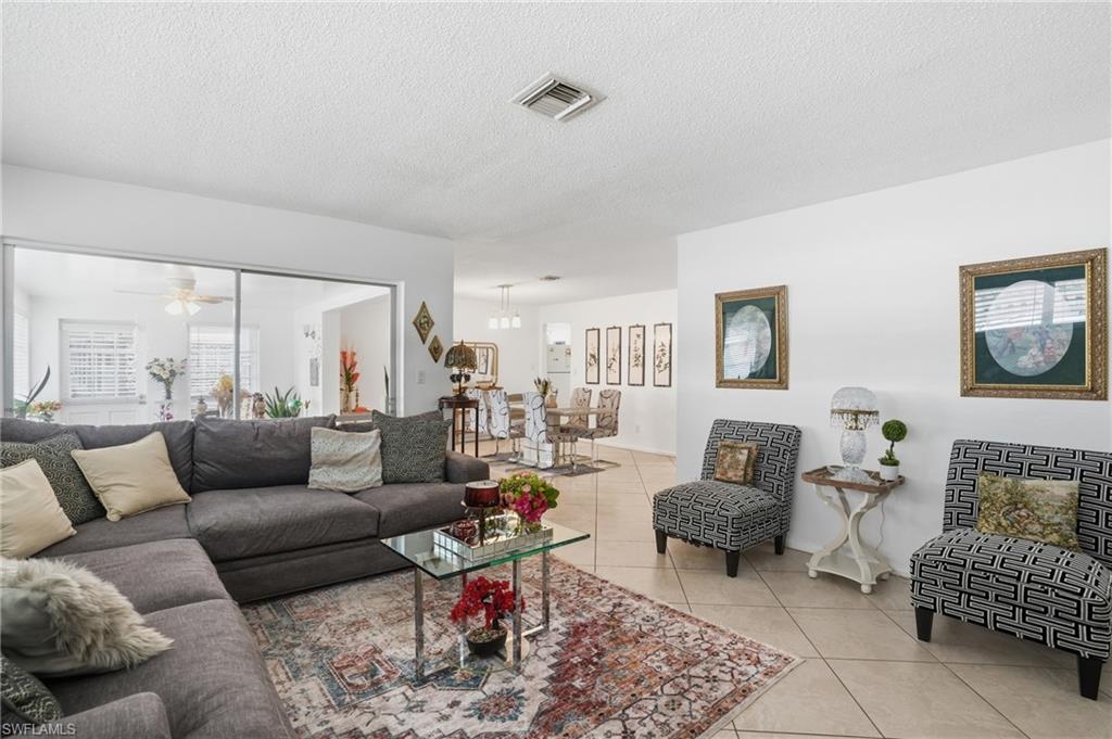 Living area featuring ceiling fan, light tile patterned floors, and a textured ceiling