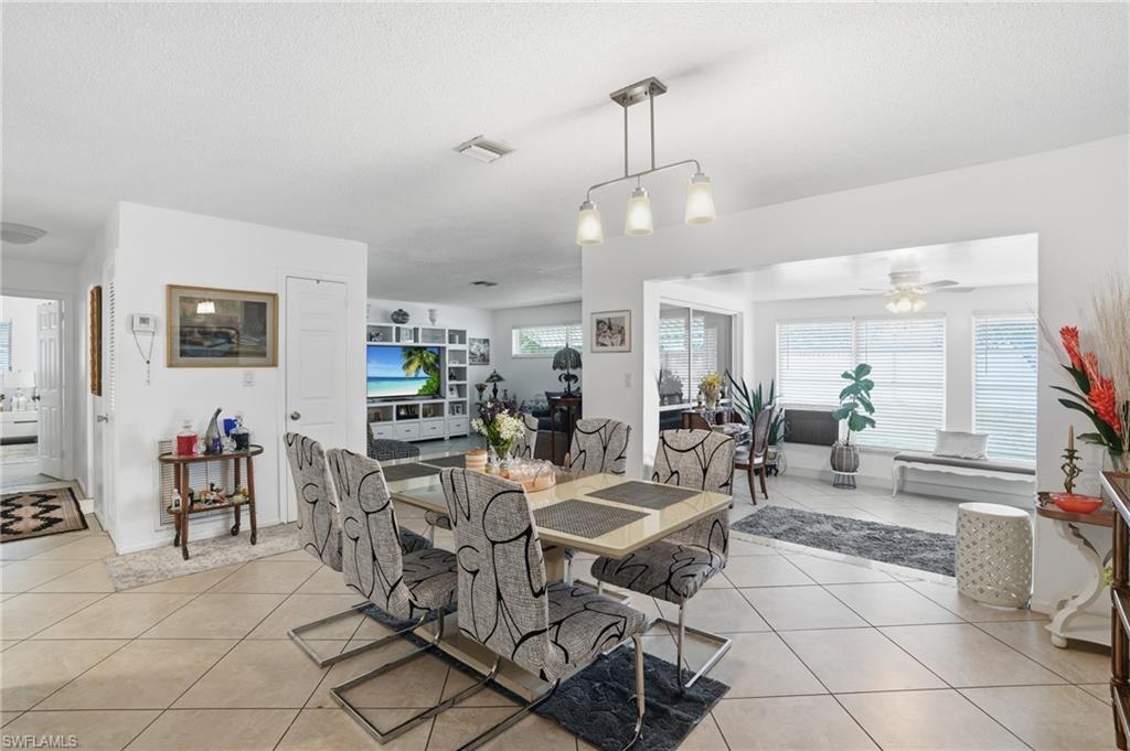 Dining area featuring ceiling fan, light tile patterned flooring, and a textured ceiling
