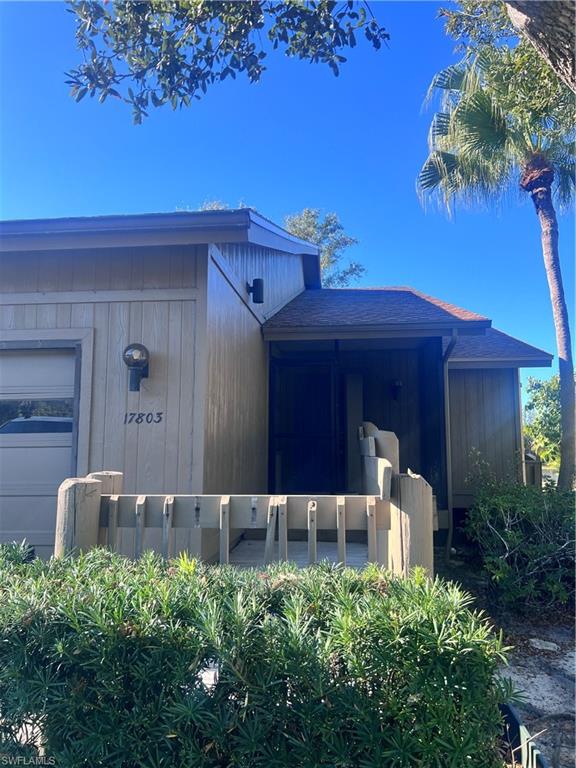 Doorway to property featuring a garage and roof with shingles