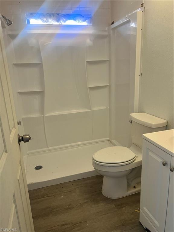 Full bath with vanity, a stall shower, and dark wood-type flooring