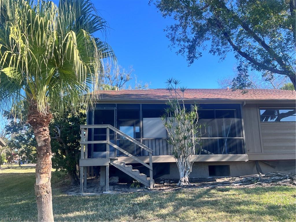 Back of property with a sunroom, a lawn, and roof with shingles