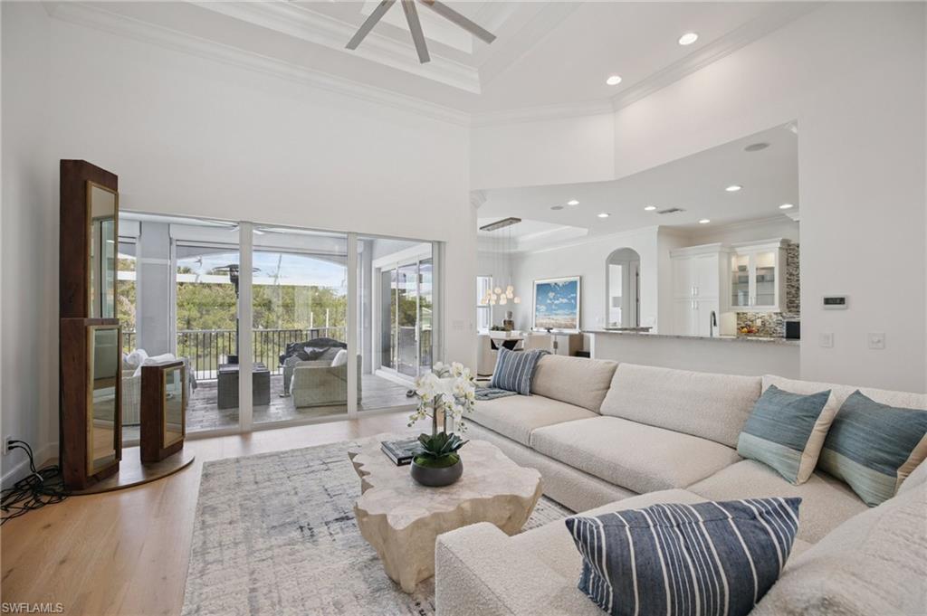 Living area featuring a coffered ceiling, ornamental molding, recessed lighting, wood flooring, and a ceiling fan