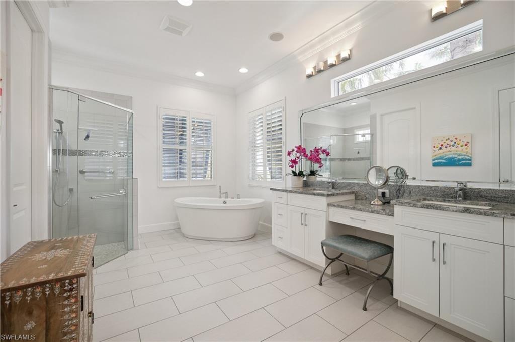 Spacious ground floor primary bathroom with vanity area, shower, crown molding, freestanding bath, and tile floor