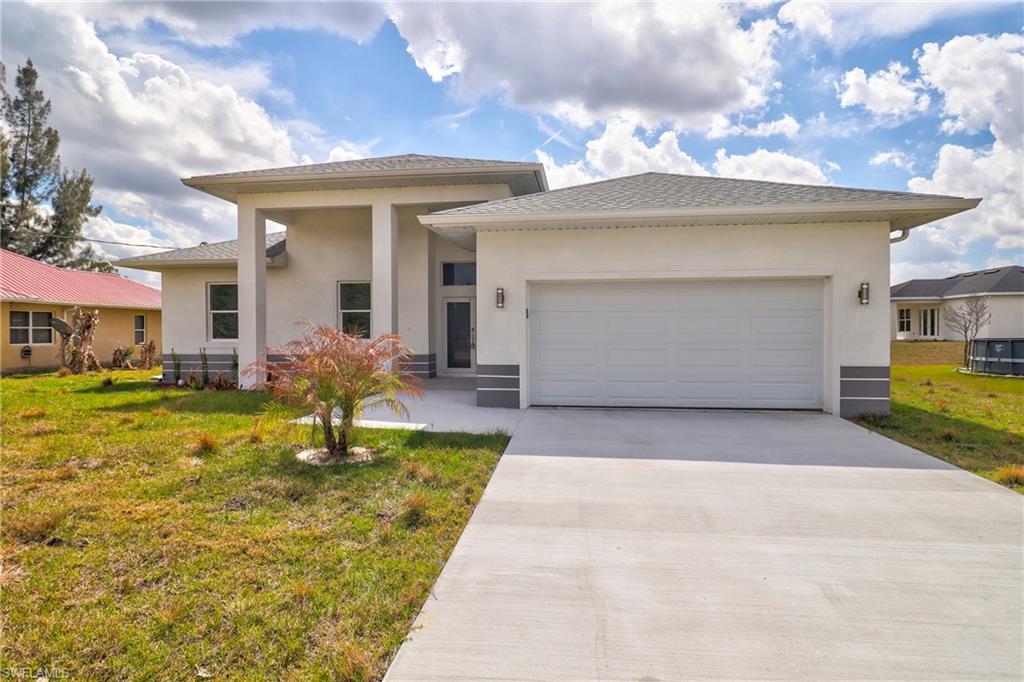Prairie-style home with a front lawn, an attached garage, concrete driveway, and stucco siding