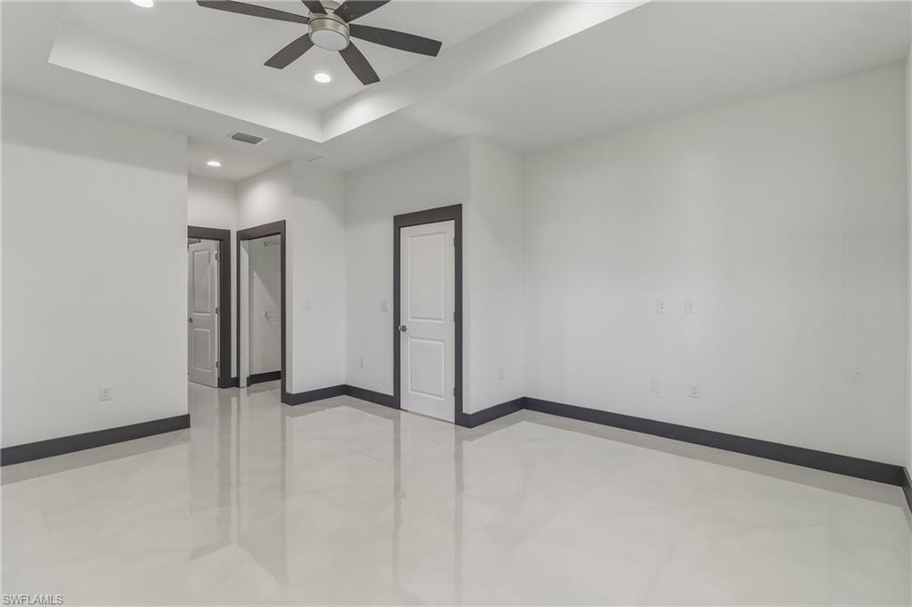 Spare room with a tray ceiling, ceiling fan, and recessed lighting